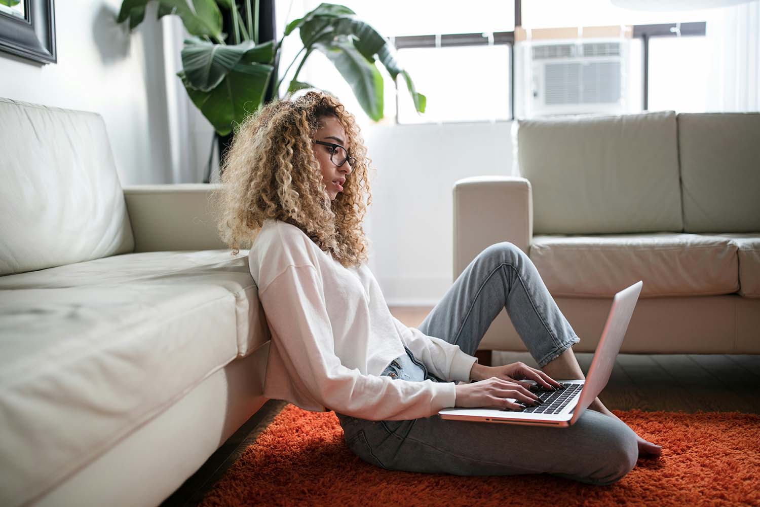 A woman with glasses reads something on her laptop.