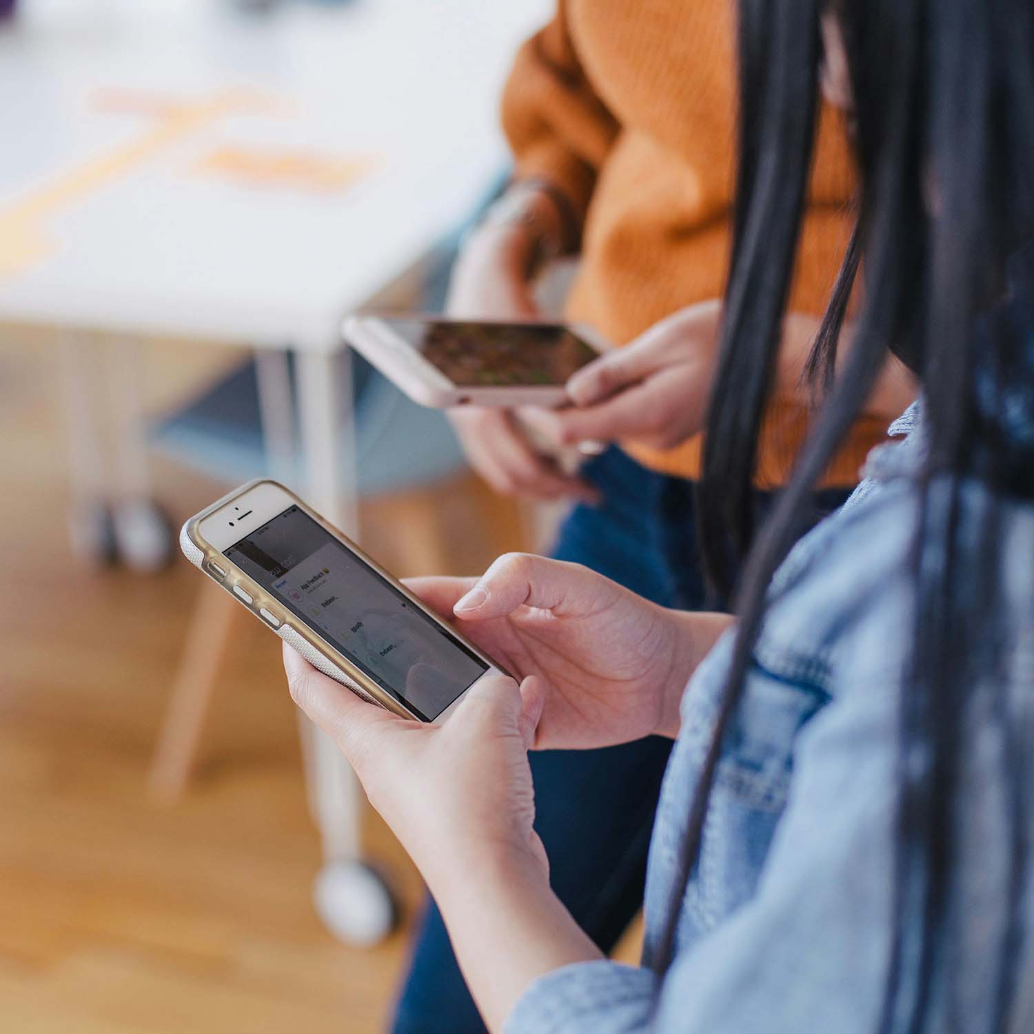 Two women use their smartphones.