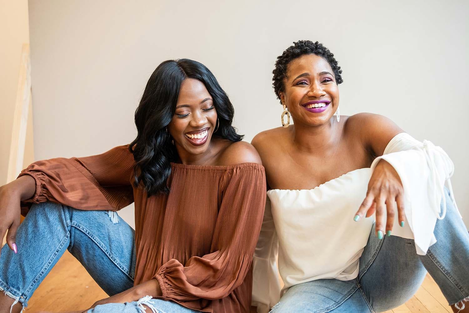 Two black women laugh together.