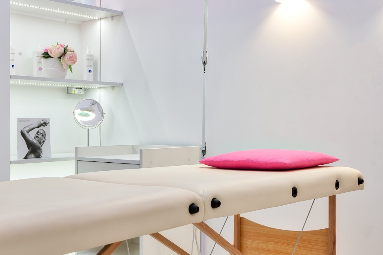 A clean, well-lit clinical space with a pink pillow on the patient table.