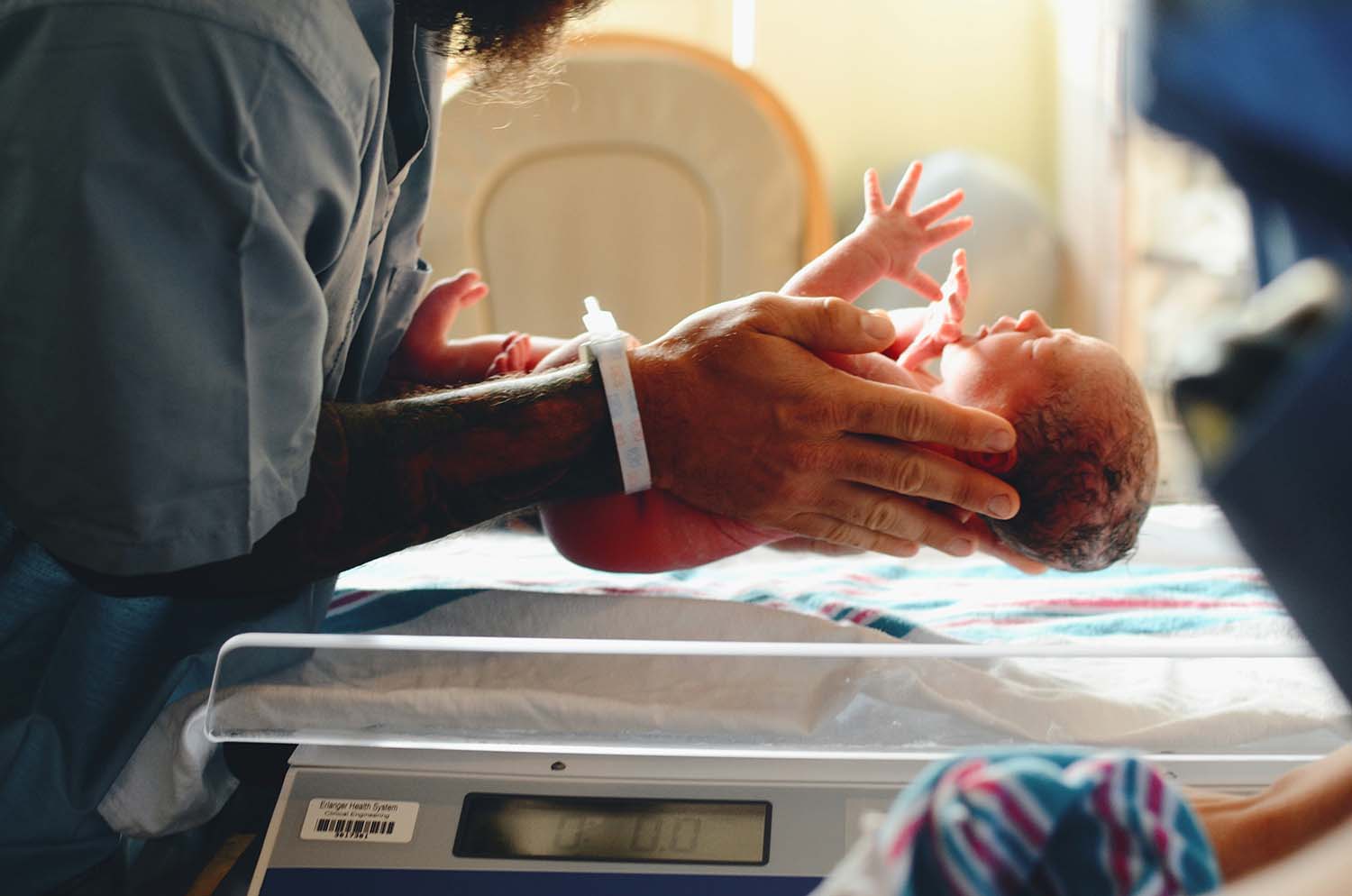 A nurse gently holds a newborn infant in their hands.