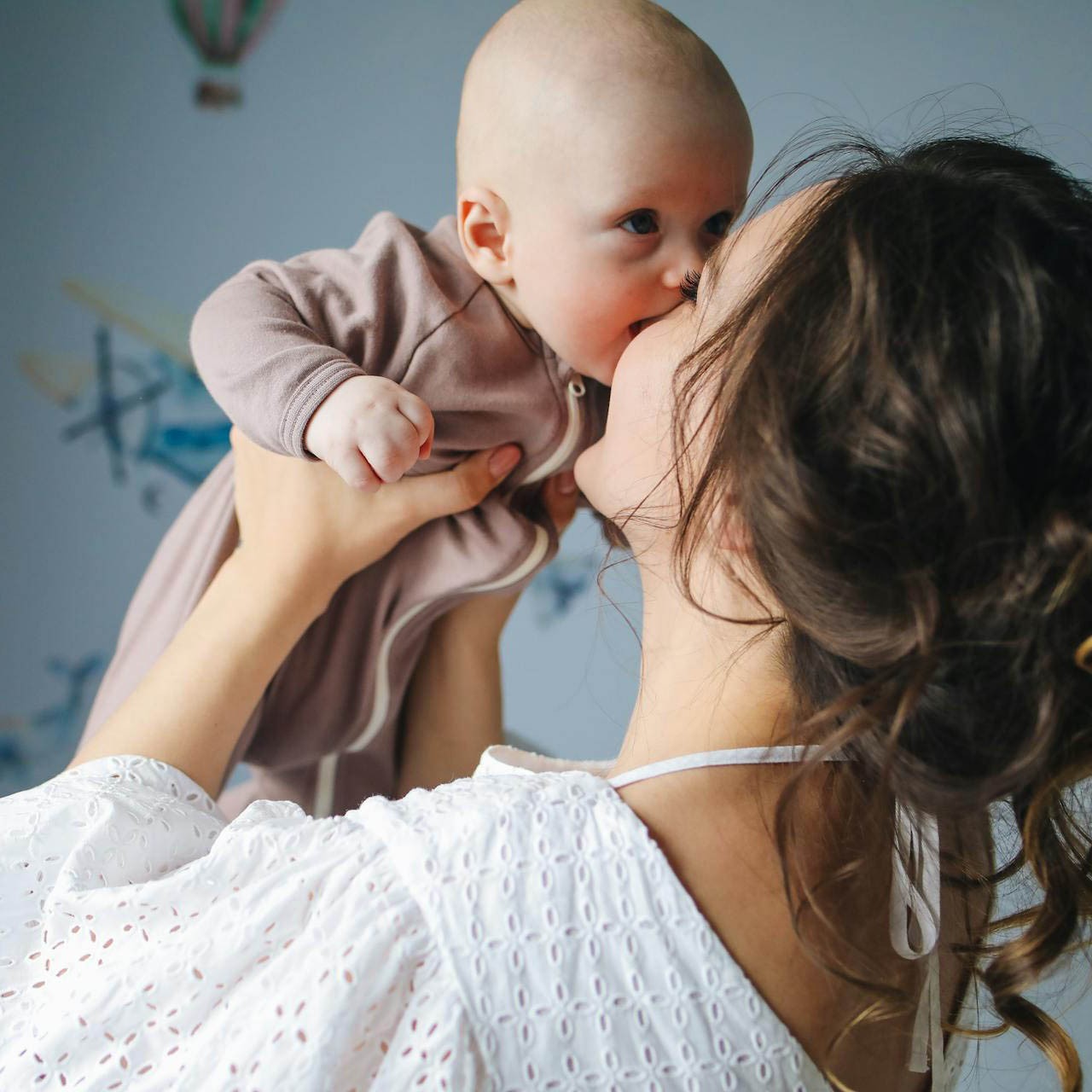 A mother holds her newborn up to her face.